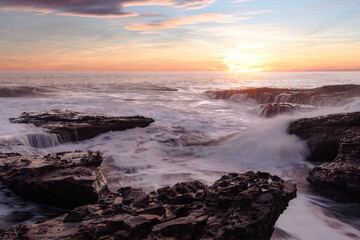 Naklejka na ściany i meble Beautiful sunrise at the coast with amazing vibrant colours and long exposure of the crashing waves 