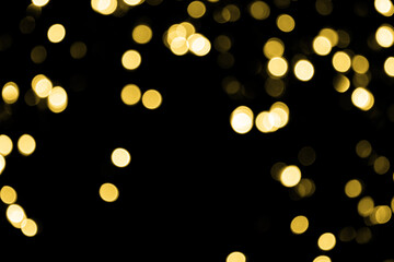 Defocused bokeh small gold lights on black background. Blurred abstract gold glitter texture. Gold bokeh glitter wallpaper for Christmas, New year or festival background.