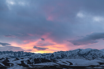 Fototapeta na wymiar colorful sunrise over snowy mountains, mountain panorama