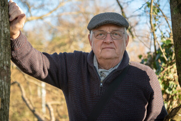 Portrait of senior man wearing a grey checked flatcap in  park in winter