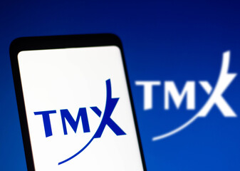 Fototapeta premium January 4, 2022, Brazil. In this photographic illustration, the logo of Toronto Stock Exchange (TMX), a stock exchange, is displayed on a smartphone with a stock market chart in the background.
