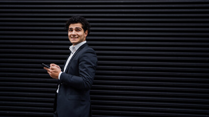 A male manager in an official suit holds a phone in his hands, writes a message to the social network