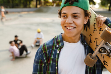 Hispanic boy smiling and holding skateboard at skate park