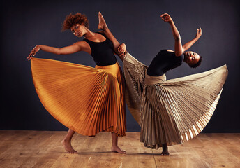 Practice and dedication make perfection. Two contemporary dancers with flowing skirts in front of a...