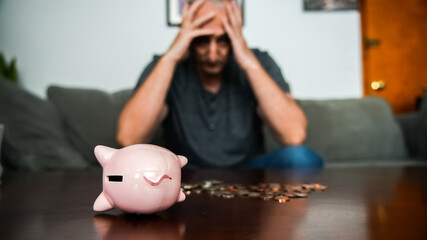 Coins and piggy bank on table with Man holding his head