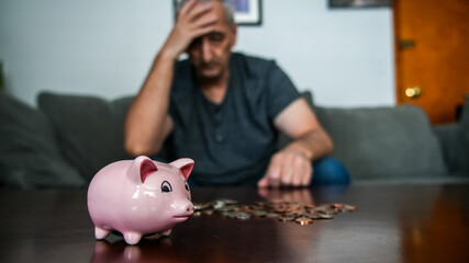 Coins and piggy bank on table with Man holding his head