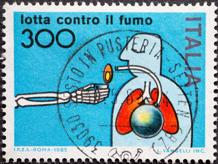 Italy - circa 1982: a postage stamp from Italy showing a skeleton that gives fire to people with...