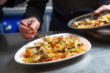 Anonymous female cook garnishing dish together