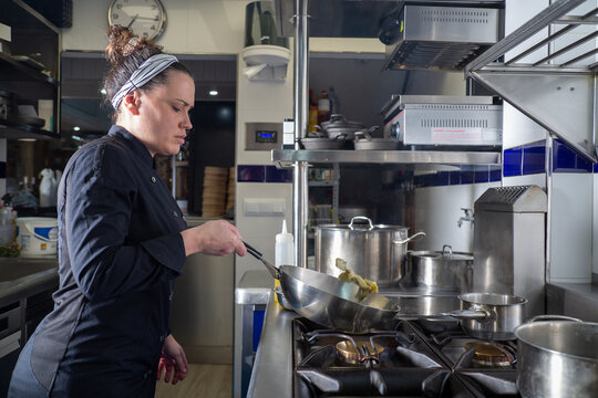 Female chef frying artichokes in kitchen