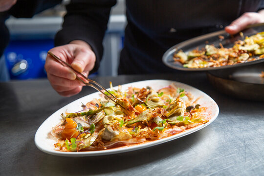 Anonymous female cook garnishing dish together