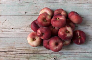 Isolated red fruit called Flat peach, Prunus persica platycarpa, also known as the doughnut peach  donut peach  Saturn peach on wooden background