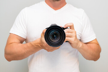 Man in a white t-shirt holding a dslr camera.