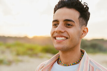 Young middle eastern man smiling during walking on beach
