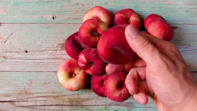 Isolated red fruit called Flat peach, Prunus persica platycarpa, also known as the doughnut peach  donut peach  Saturn peach on wooden background