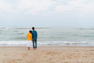Multiracial couple holding hands while walking on beach