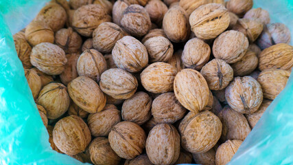 Pile of shelled walnuts in plastic bag. Top or above view of traditional hard brown nuts. Agricultural clean eating concept.