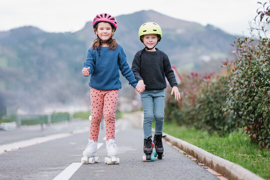 Kids holding hands riding on roller skates on road