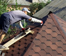 the roofer lubricates the roof surface with mastic from a wooden platform at the very top of the gazebo