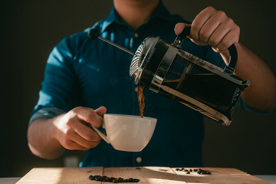 Crop man pouring coffee from French press into cup