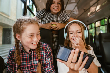 Girls laughing and using cellphone while going on school bus