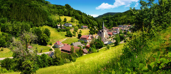 Panoramic gorgeous landscape containing an idyllic German village in a lush green valley in the...