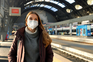 Portrait of business woman waiting train wearing medical protective mask at train station in winter