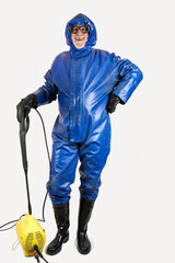 Ready for the high pressure cleaning. A workman in protective suit, rubber gloves, rubber boots and...