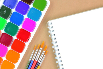 Watercolor paints and brushes with sketch pad, creative mockup for banner or text, copy space.