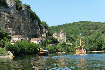 View of the magnificent village of Sarlat in Dordogne, France.  Amazing medieval castle, large rock and two wonderful and romantic boats in the river called barge, tipycal in this area.