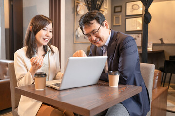 カフェでパソコンで打ち合わせをする男女のビジネスマン