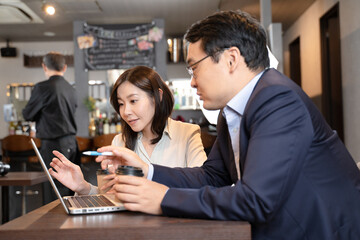 カフェでパソコンで打ち合わせをする男女のビジネスマン