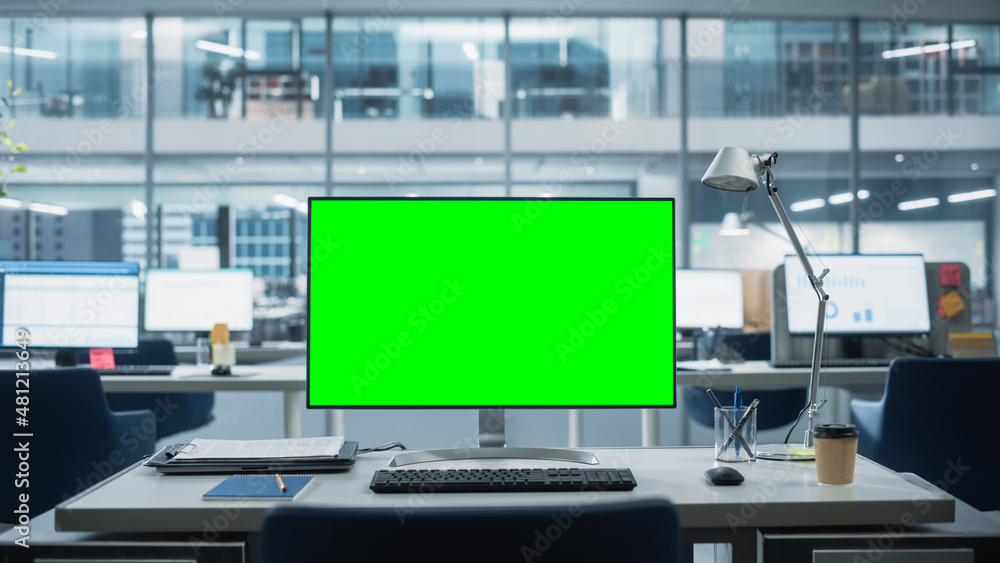 Poster Desktop Computer Monitor with Mock Up Green Screen Chroma Key Display Standing on the Desk in the Modern Business Office. In the Background Glass Wall with Big City Office.
