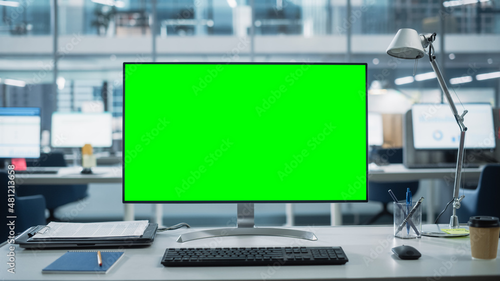 Poster Desktop Computer Monitor with Mock Up Green Screen Chroma Key Display Standing on the Desk in the Modern Business Office. In the Background Glass Wall with Big City Office.