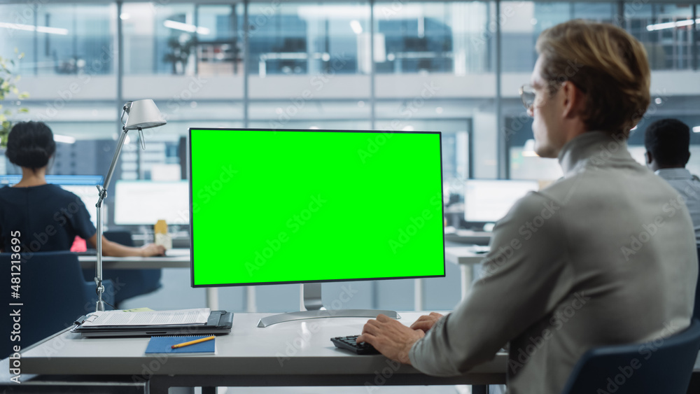 Fototapete Close Up Over the Shoulder Shot of a Businessman Working on Desktop Computer with Chroma Key Green Screen Mock Up Display. Digital Projects Manager Typing Data, Using Keyboard and Mouse.