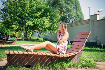 Portrait of a beautiful girl in the summer on a chaise longue