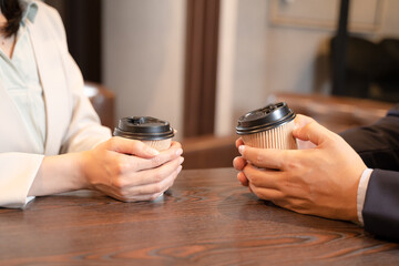 カフェでコーヒーを飲みながら話をする恋人夫婦