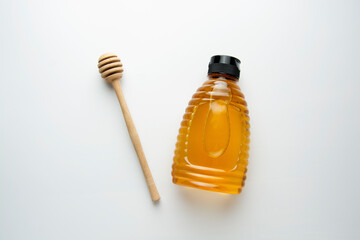 Plastic jar bottle with honey honey spoon, on white background