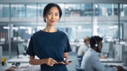 Successful Businesswoman in Stylish Dress Holding Tablet Computer, Standing in Modern Diverse Office Working on Financial, Business and Marketing Projects. Portrait of Beautiful Asian Manager.