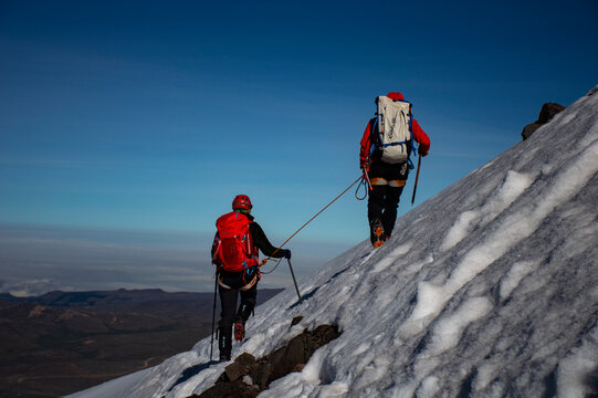 Mountain guide taking care of her client on a snow covered slope in Chimborazo volcano. 