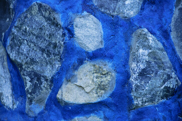 Fragment of masonry. Stones in concrete on blue background are laid out in the form of continents.