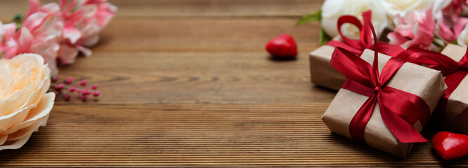 Valentine's day baner. Gift boxes and flowers on wooden background with copy space.