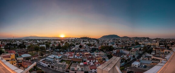 Fototapeta na wymiar Panoramic photography of the city of Toluca, Mexico, distinguishing the houses, buildings, streets, the sunset and the famous Nevado de Toluca Volcano.