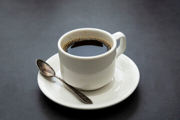 Coffee cup isolated. White cup of coffee top view spoon and plate on dark background