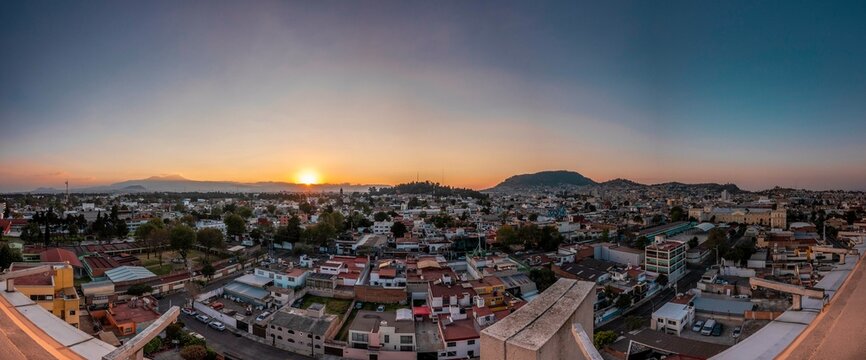 Panoramic photography of the city of Toluca, Mexico, distinguishing the houses, buildings, streets, the sunset and the famous Nevado de Toluca Volcano.