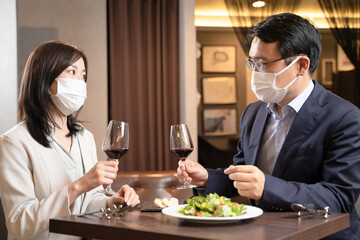 飲食店でマスク会食をする男女