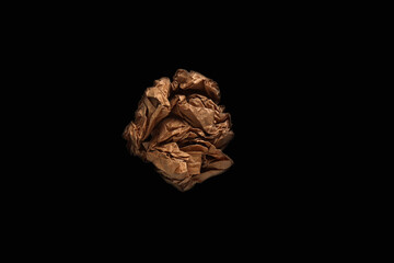 A lump of crumpled brown Kraft paper isolated on a black background