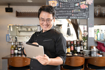 飲食店でタブレットを操作する男性スタッフ
