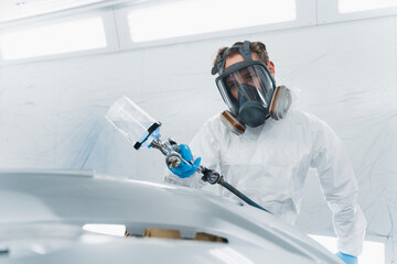 Car painter varnishing car bumper. Auto body repair process
