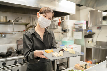 感染症対策のマスクをして食事提供する女性スタッフ