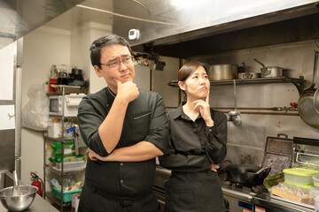 飲食店で困ったポーズをする男女のスタッフ